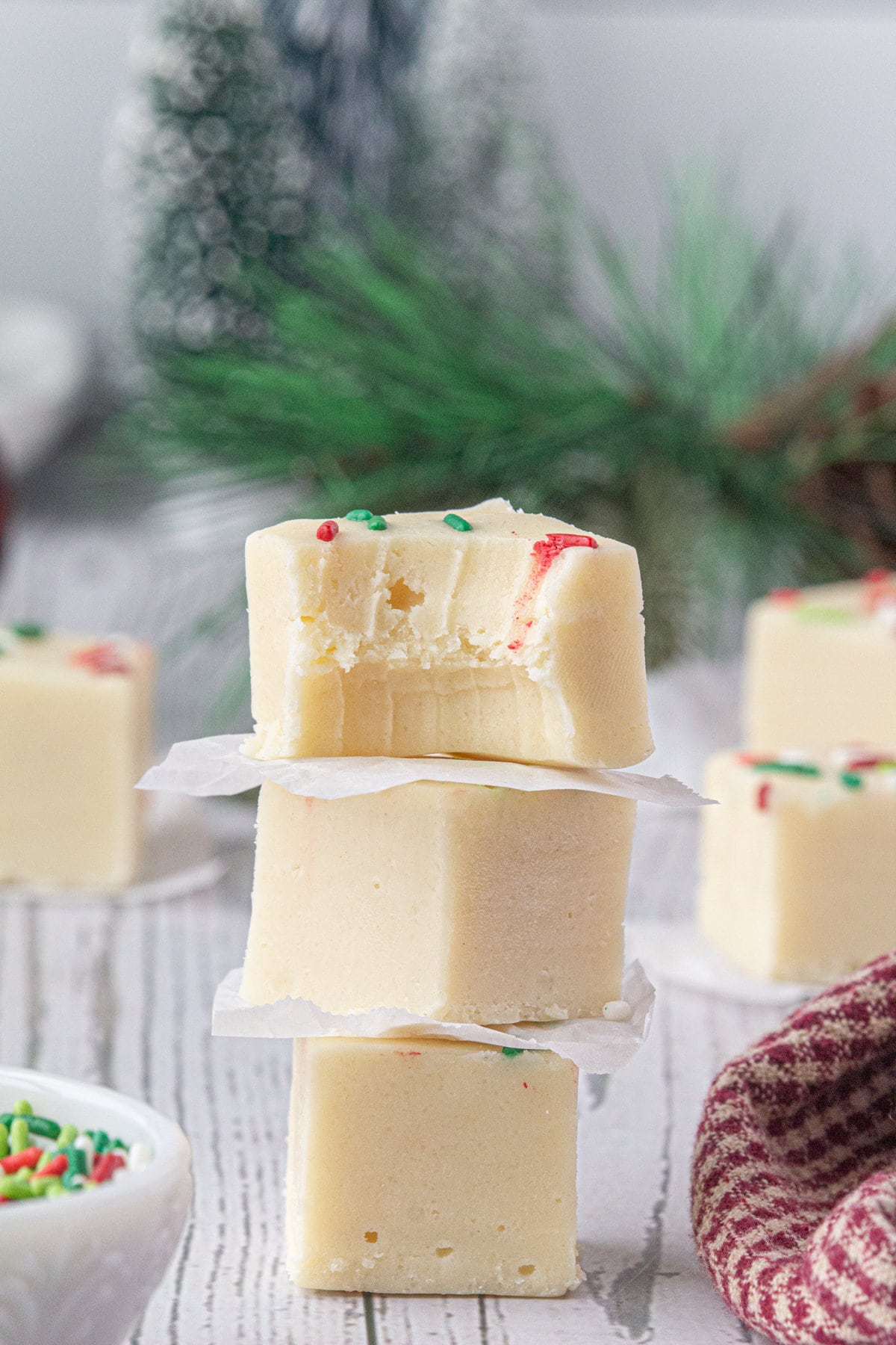 Three pieces of stacked Christmas cookie fudge. You can see the sprinkles on the top piece and a bite is taken out of it.