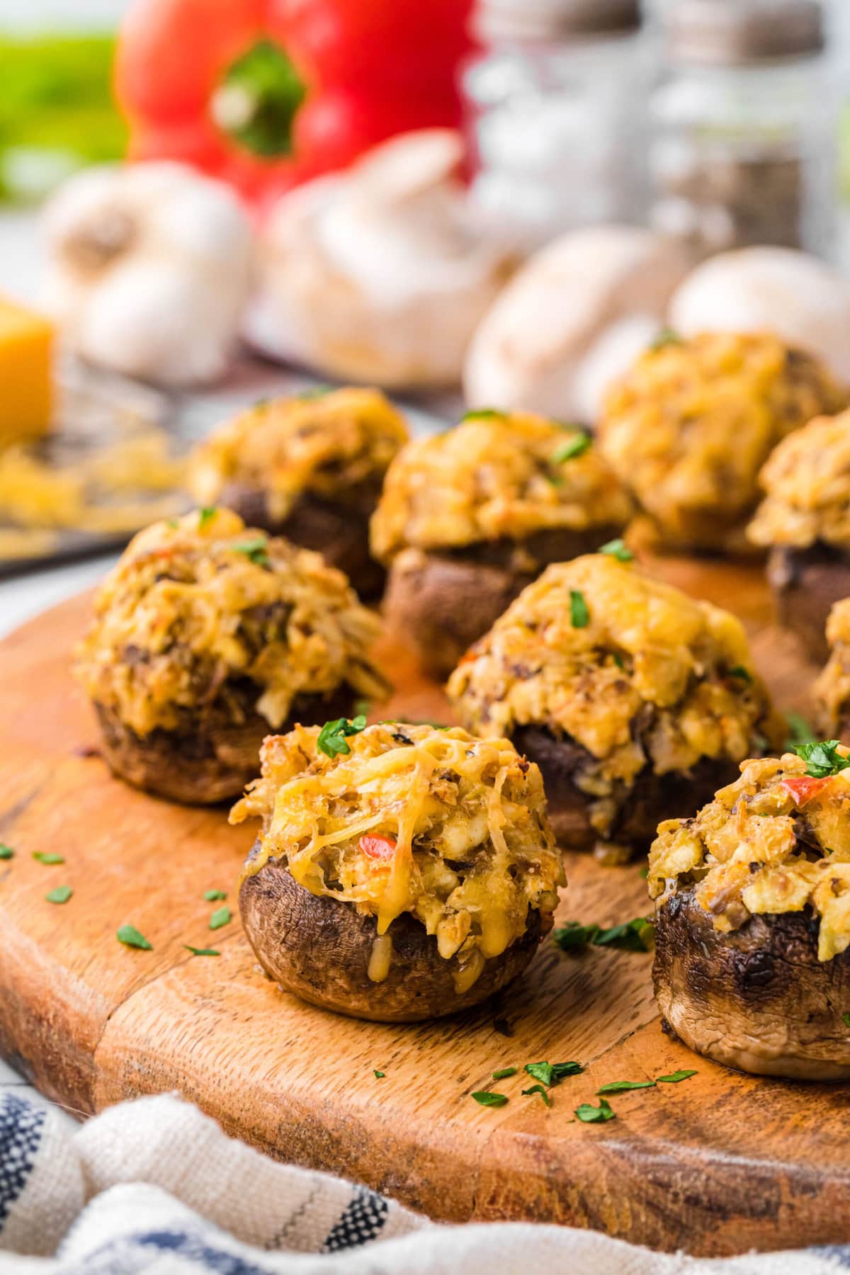 Stuffed mushrooms topped with melted cheese sit on a wooden platter.