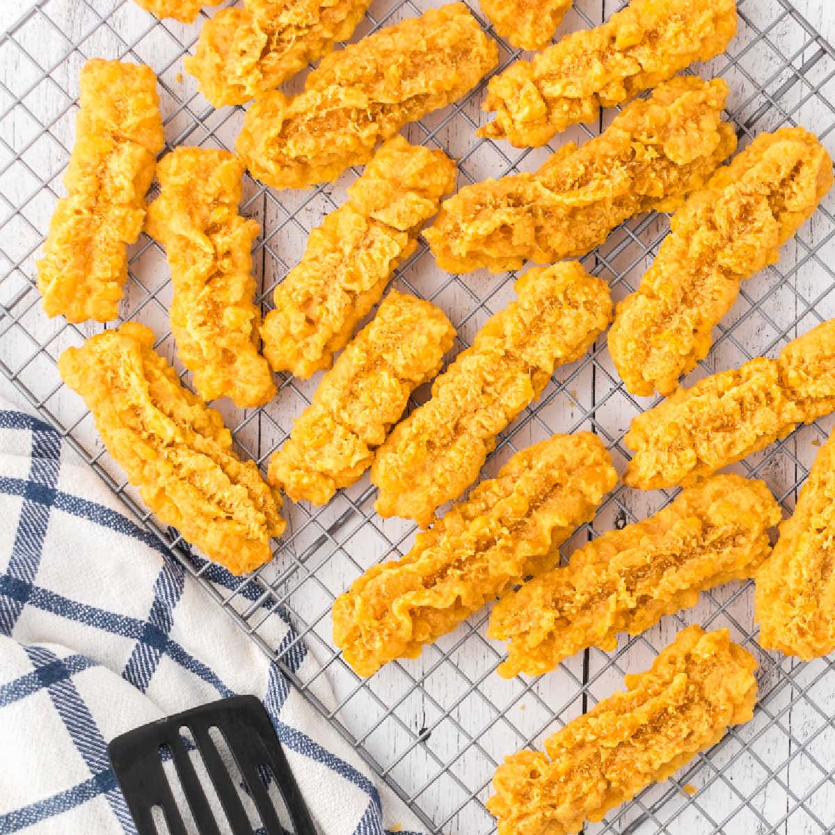 Overhead view of cheese straws cooling on a wire rack.