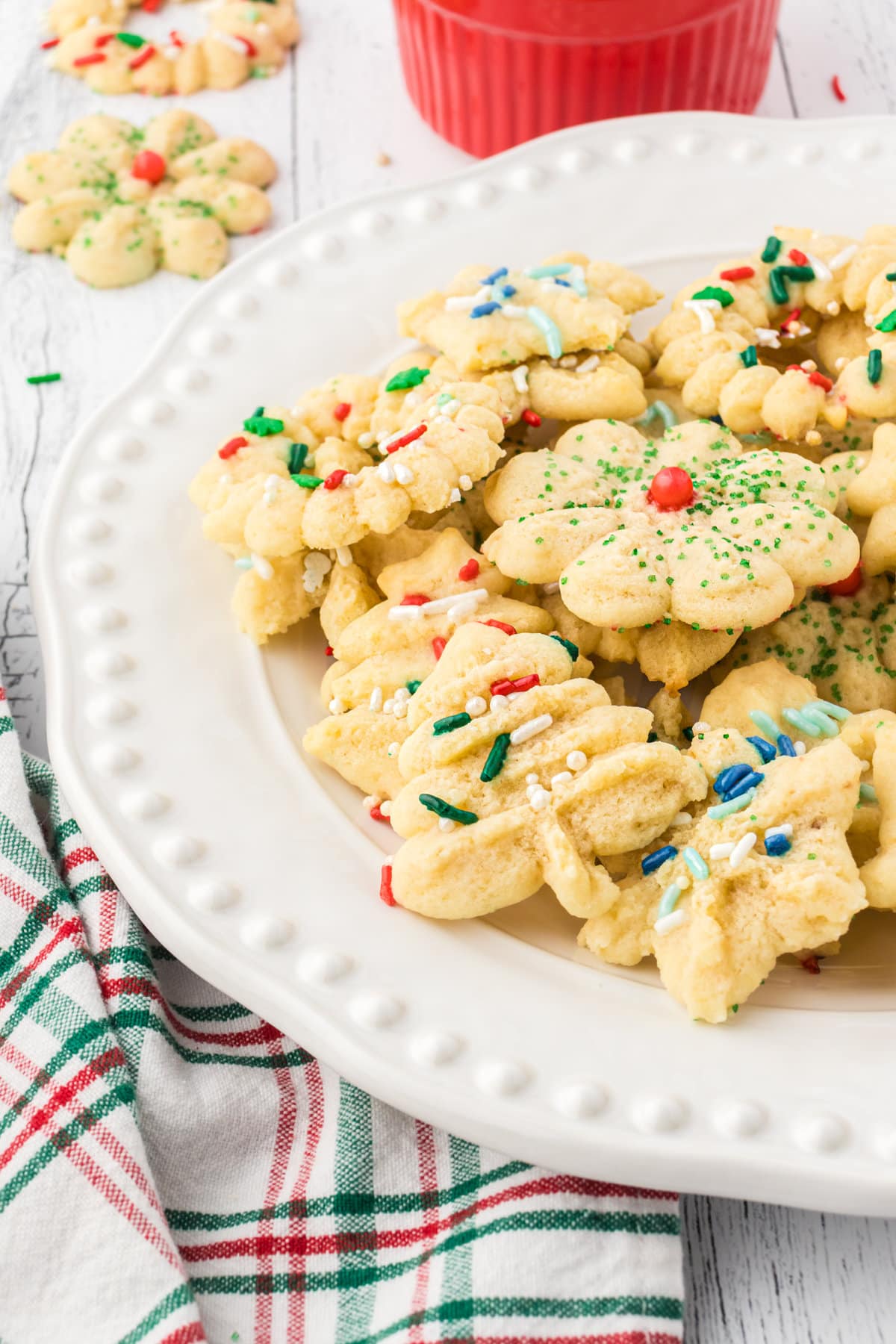 A white plate filled with Christmas sprinkle-coated spritz cookies.