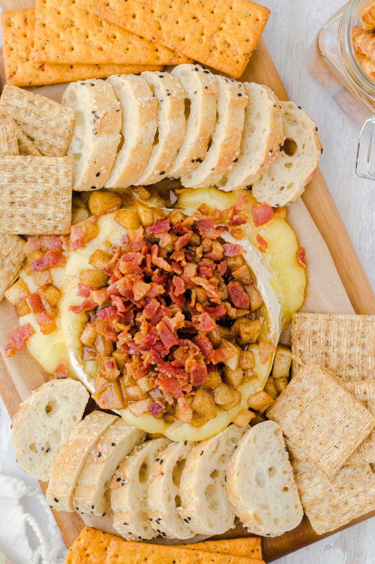 Overhead view of baked brie on a board surrounded by crackers.