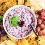 Overhead view of cranberry jalapeno dip on a snack board surrounded by crackers and fruit. A text title overlay is across the top.