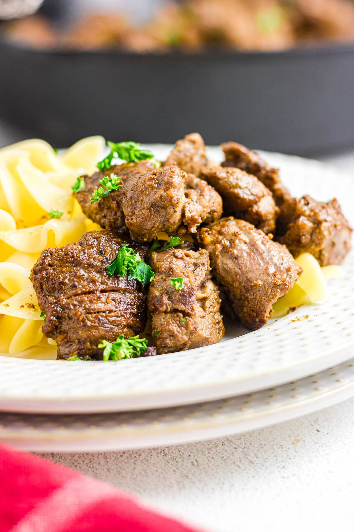 A close-up view of steak tips on top of a bed of noodles.