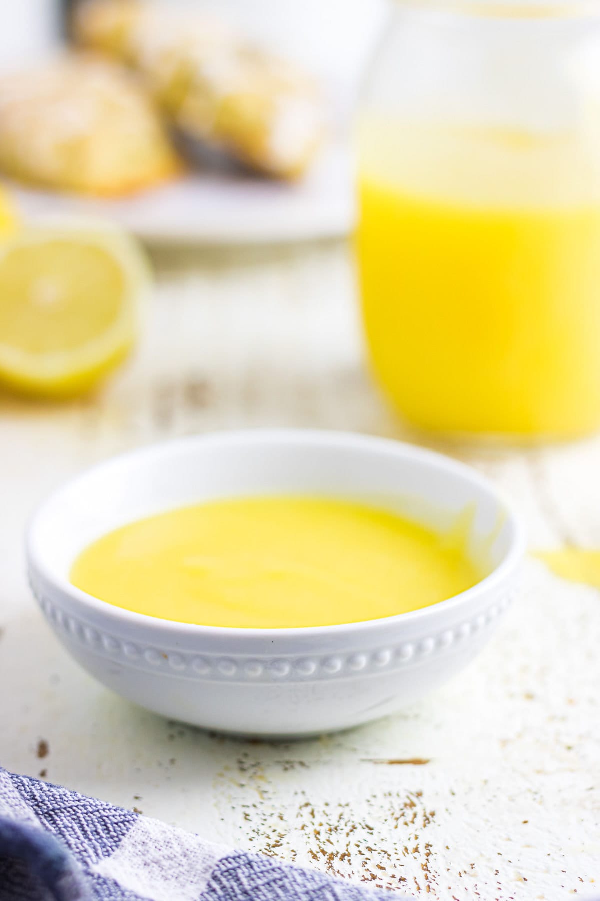 A bowl of lemon curd on a white wooden table.