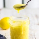 A spoonful of lemon curd being lifted from the jar.