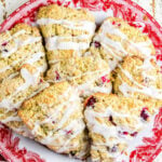 Overhead view of cranberry orange scones on a red plate with title text overlay for Pinterest.
