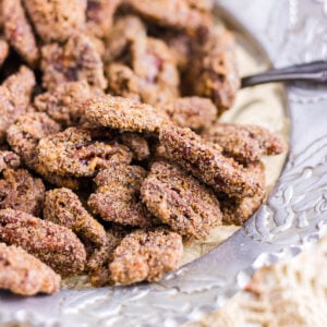 Closeup of pecans in a serving dish showing the bumpy texture of the crunchy candied pecans.