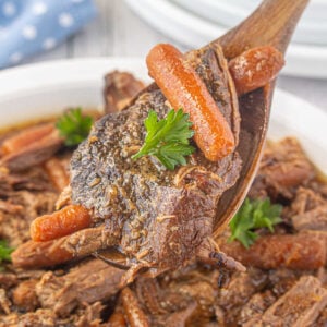 A close up of roast and carrots being spooned from the slow cooker.