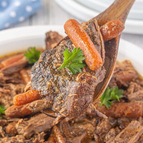 A close up of roast and carrots being spooned from the slow cooker.