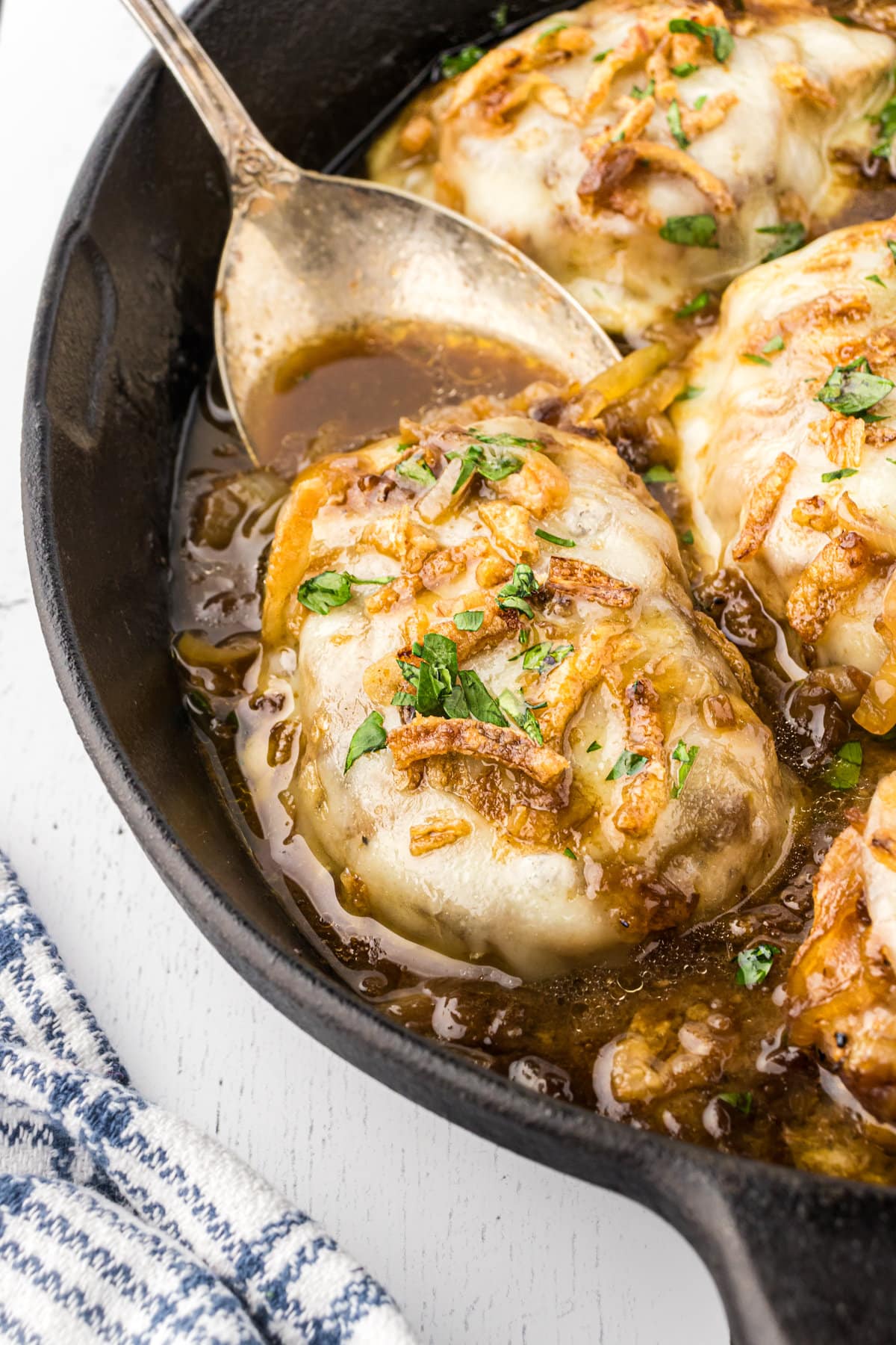 Cheesy French onion pork chops shown up-close in a skillet.