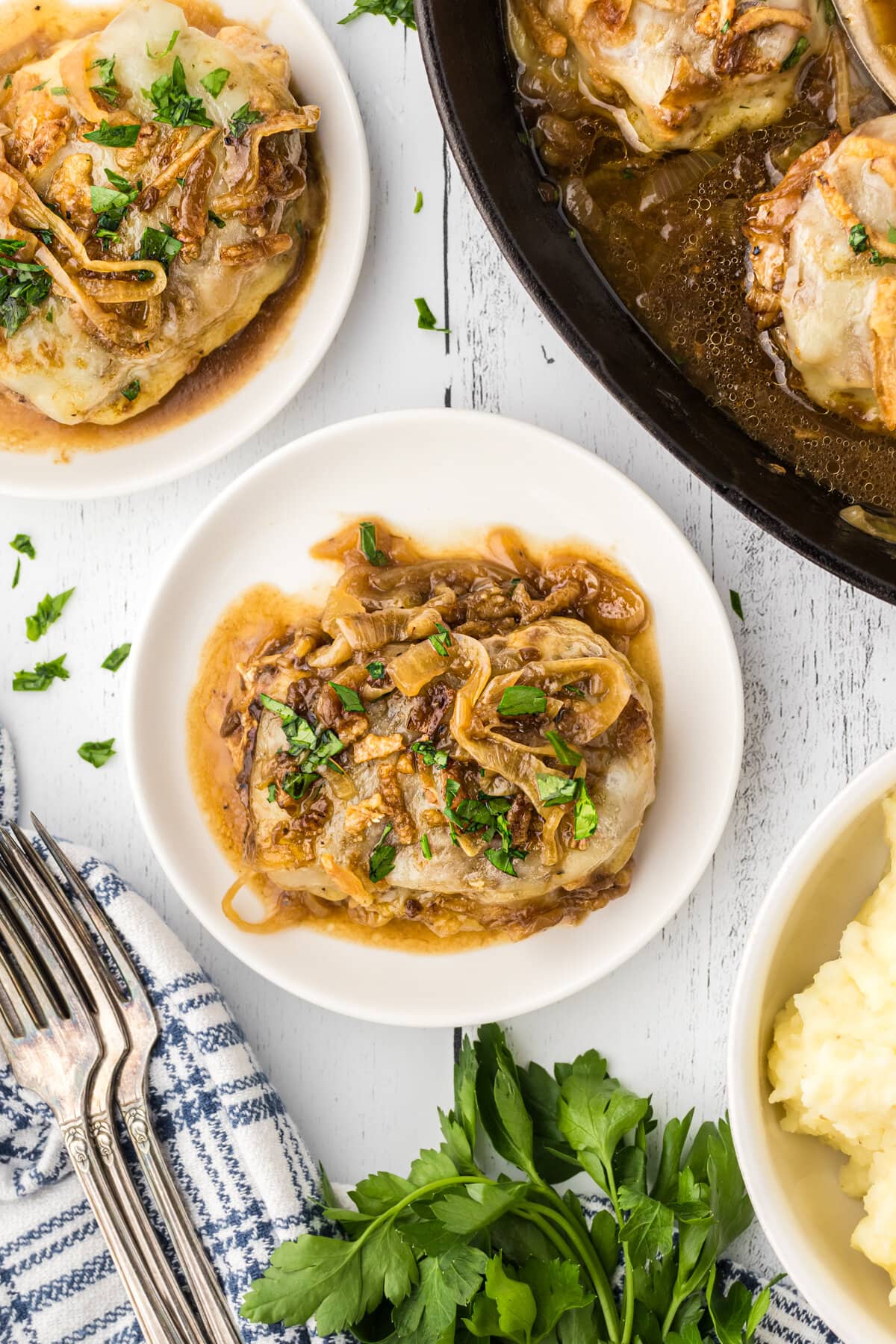 Pork chops topped with onions and cheese on a white plate.