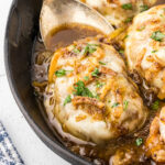 Closeup of a juicy pork chop covered in onions and provolone cheese.