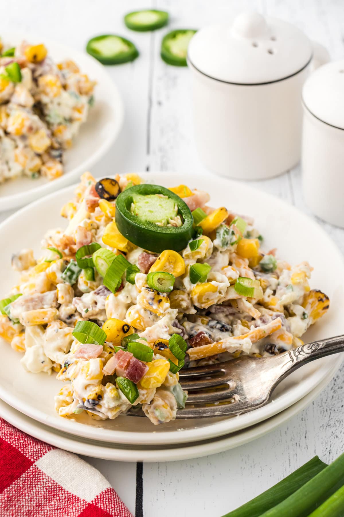 An up-close photo of corn popper salad topped with a fresh jalapeno slice on a small plate.