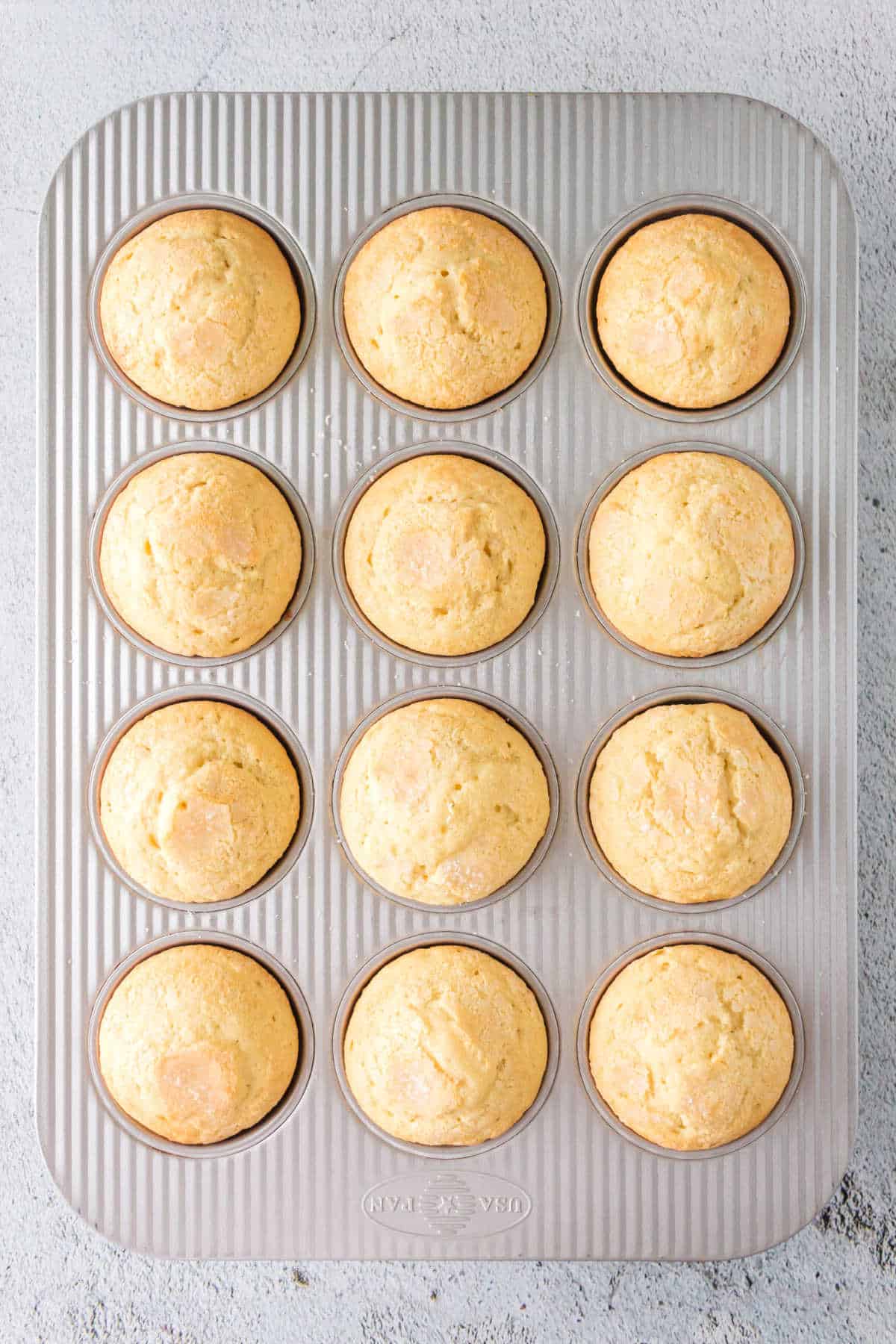 Overhead view of a pan full of golden brown vanilla muffins.