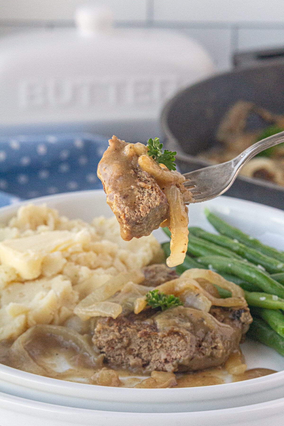 A close-up photo of a bite of liver topped with onions and gravy.