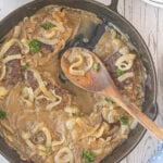 Overhead view of liver and onions in a cast iron skillet.