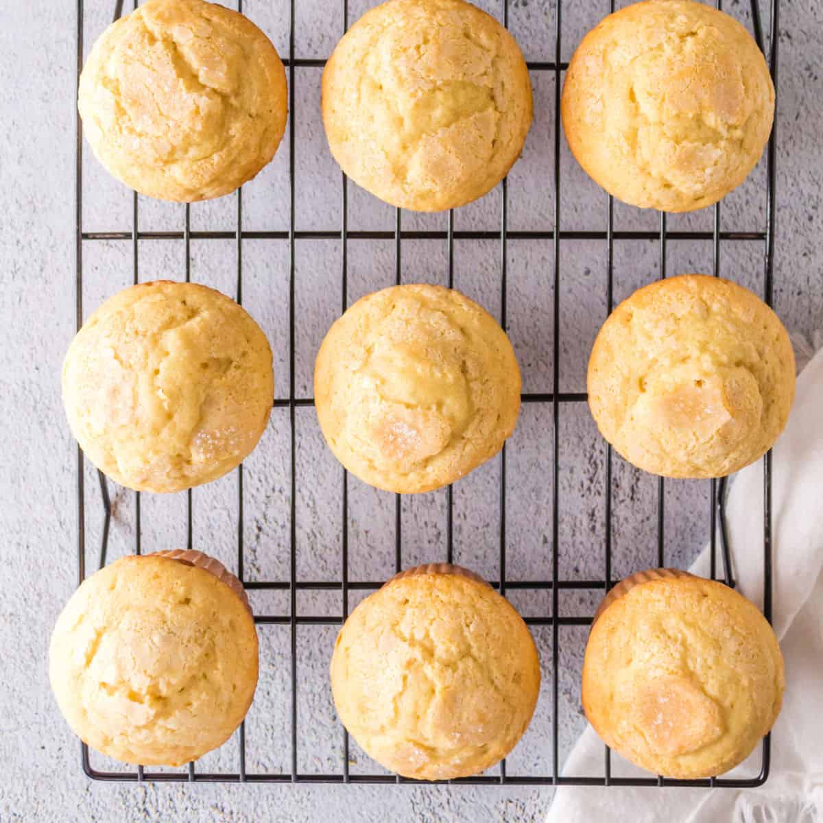 Overhead view of golden brown vanilla muffins cooling on a wire rack.