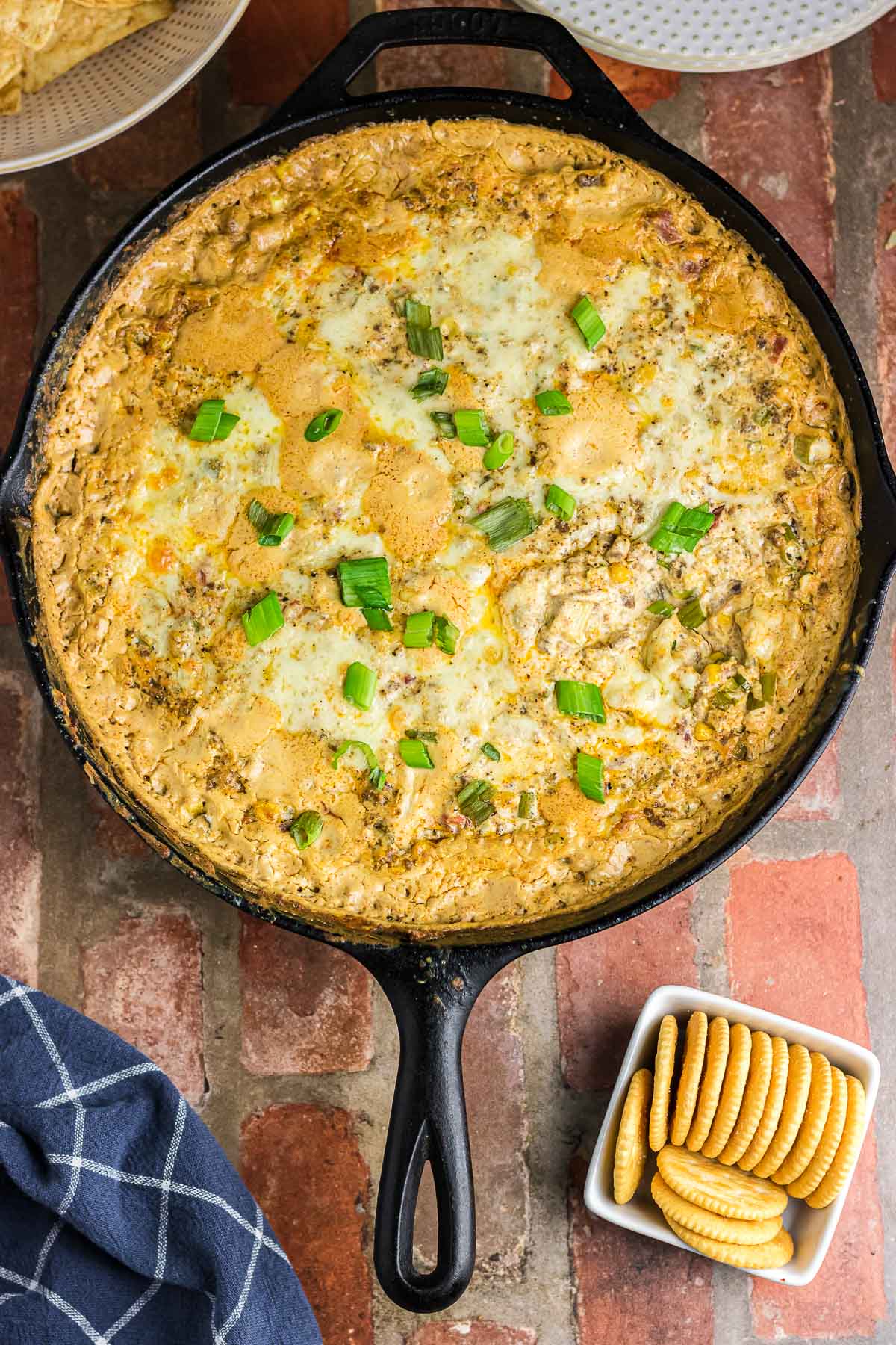 Baked cowboy dip in a skillet next to some crackers.