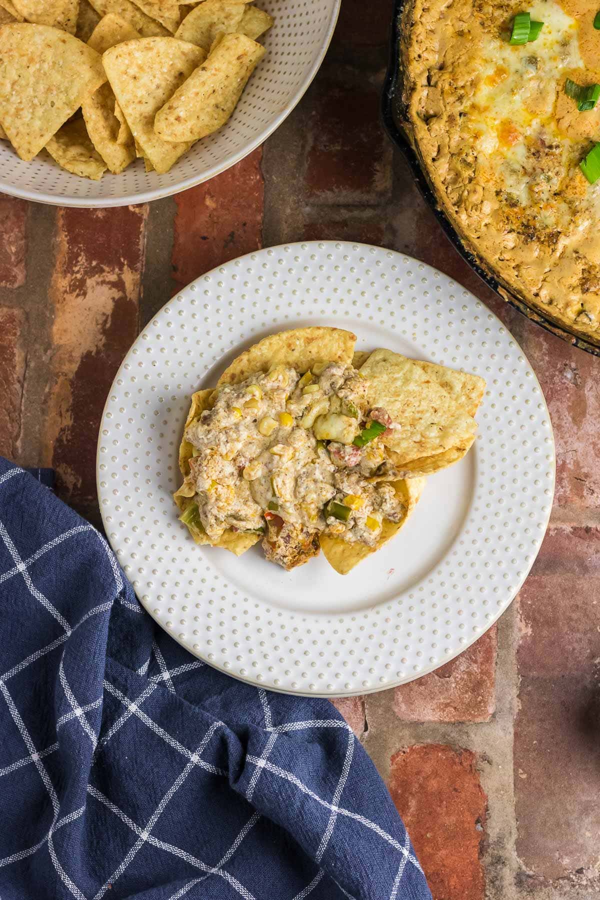 Cowboy dip on top of a pile of tortilla chips on a plate.