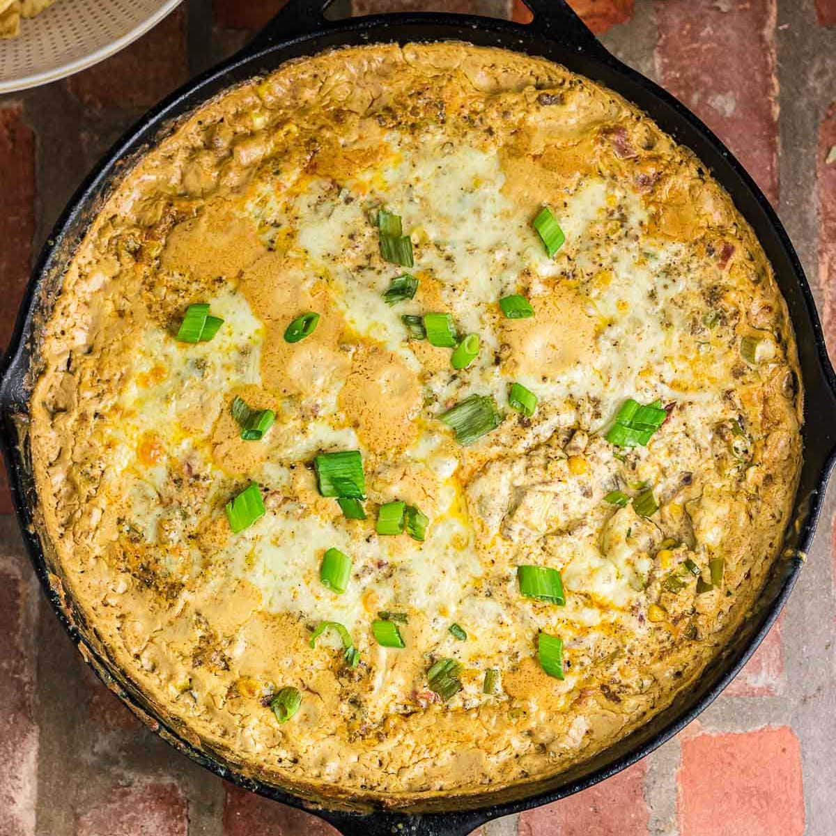 Overhead view of baked cowboy dip in an iron skillet.