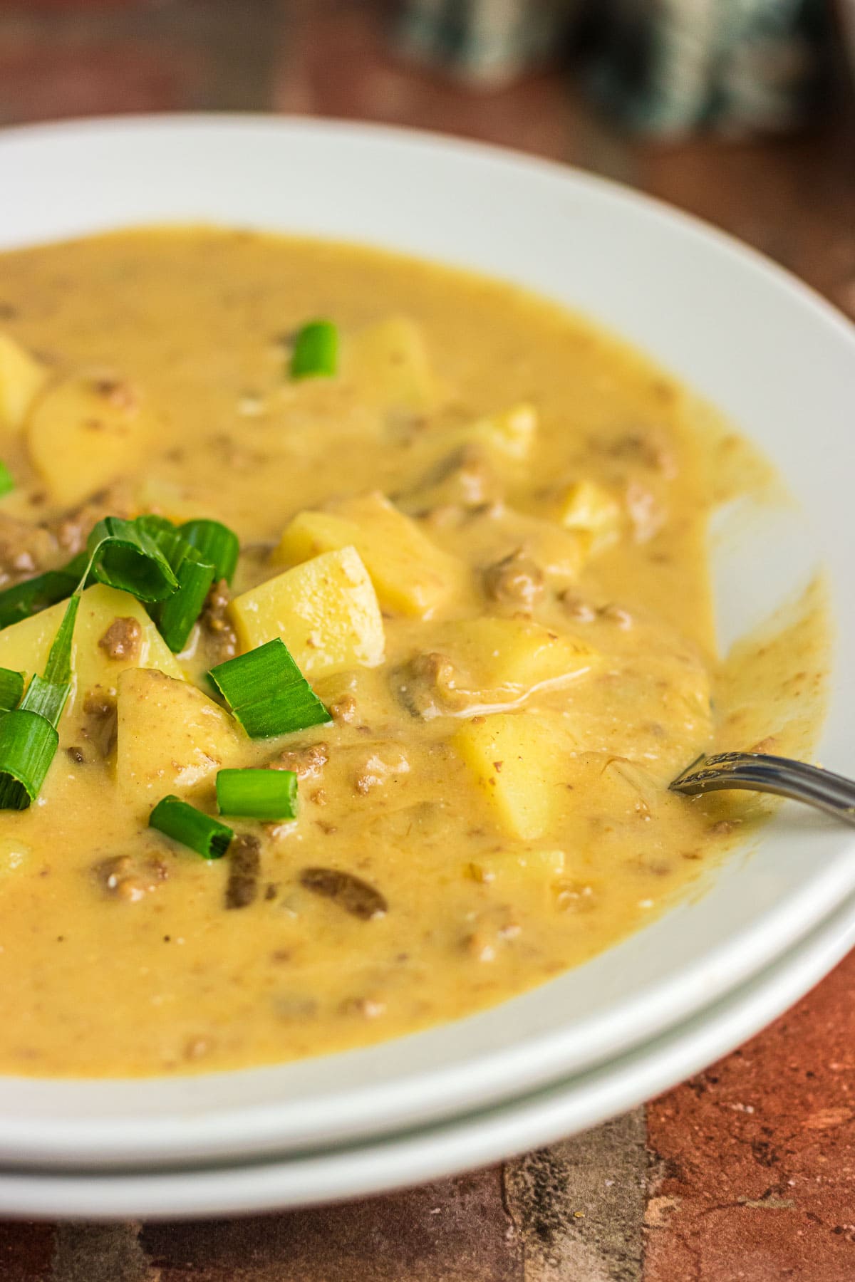 A close-up photo of cheeseburger soup in a dinner bowl.