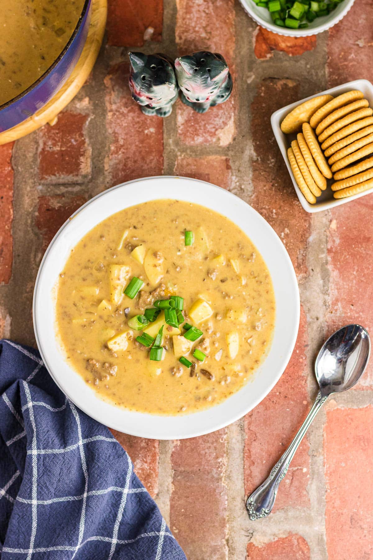 An overhead view of cheeseburger soup with potatoes in a dinner bowl.