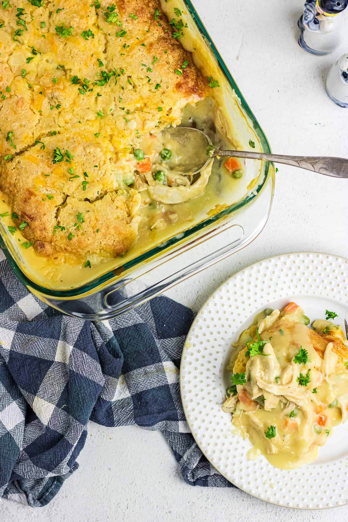 A plate topped with a scoop of chicken cobbler next to the baking dish with the rest of the casserole.