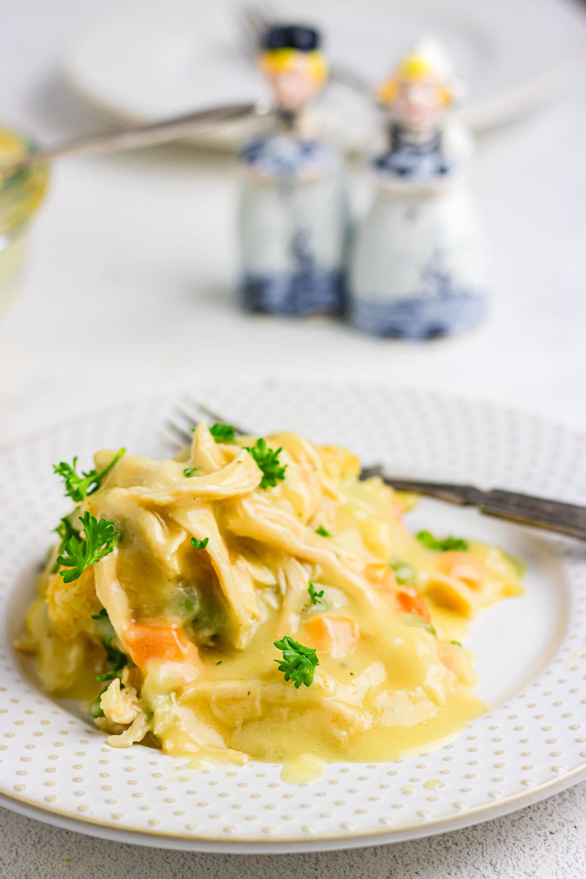 An up-close photo of chicken cobbler on a white plate, topped with parsley.