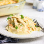 A serving of chicken cobbler on a white plate with creamy gravy spilling over the plate.