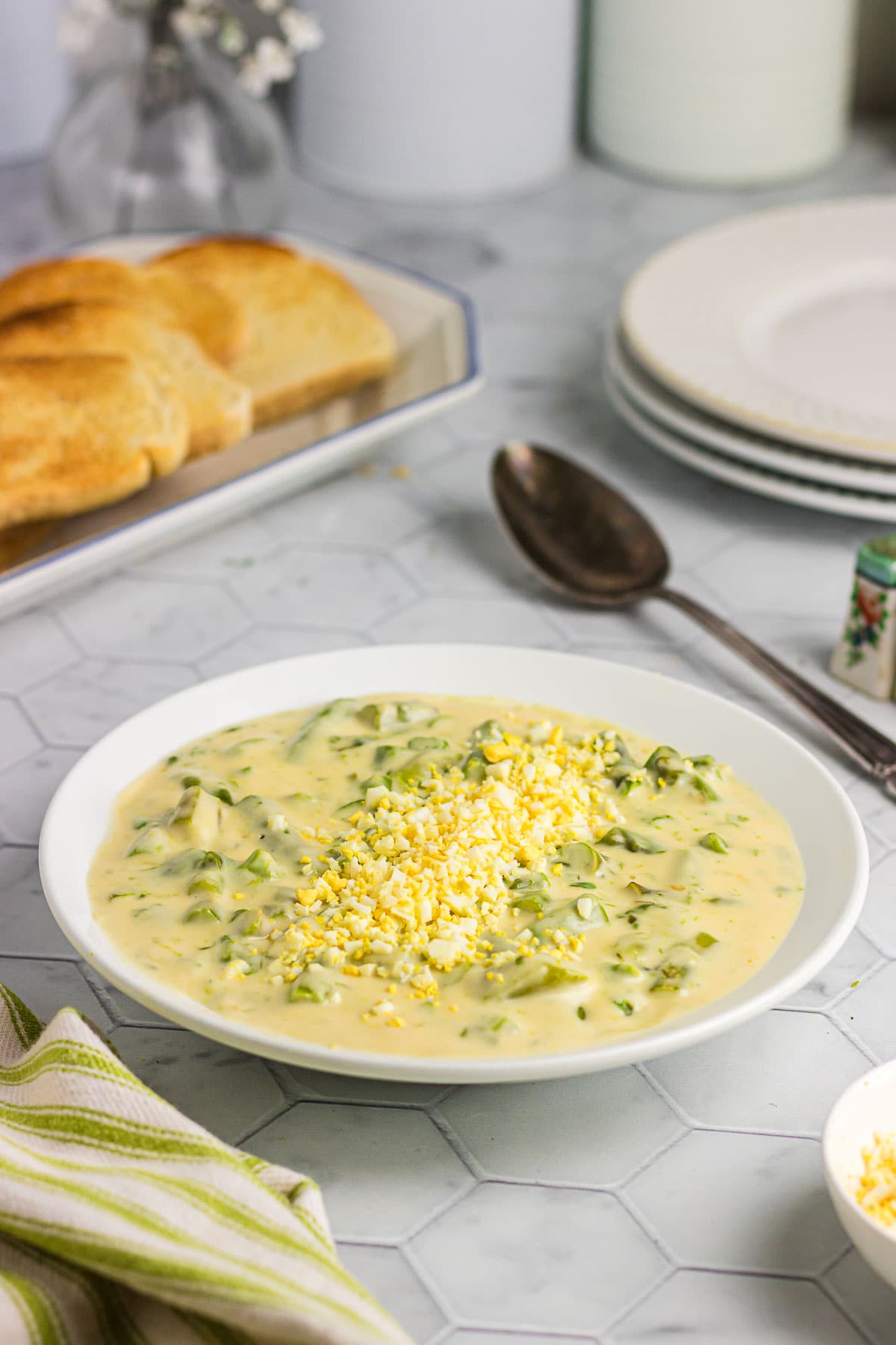 A closeup view of creamed asparagus in a serving bowl next to toast.