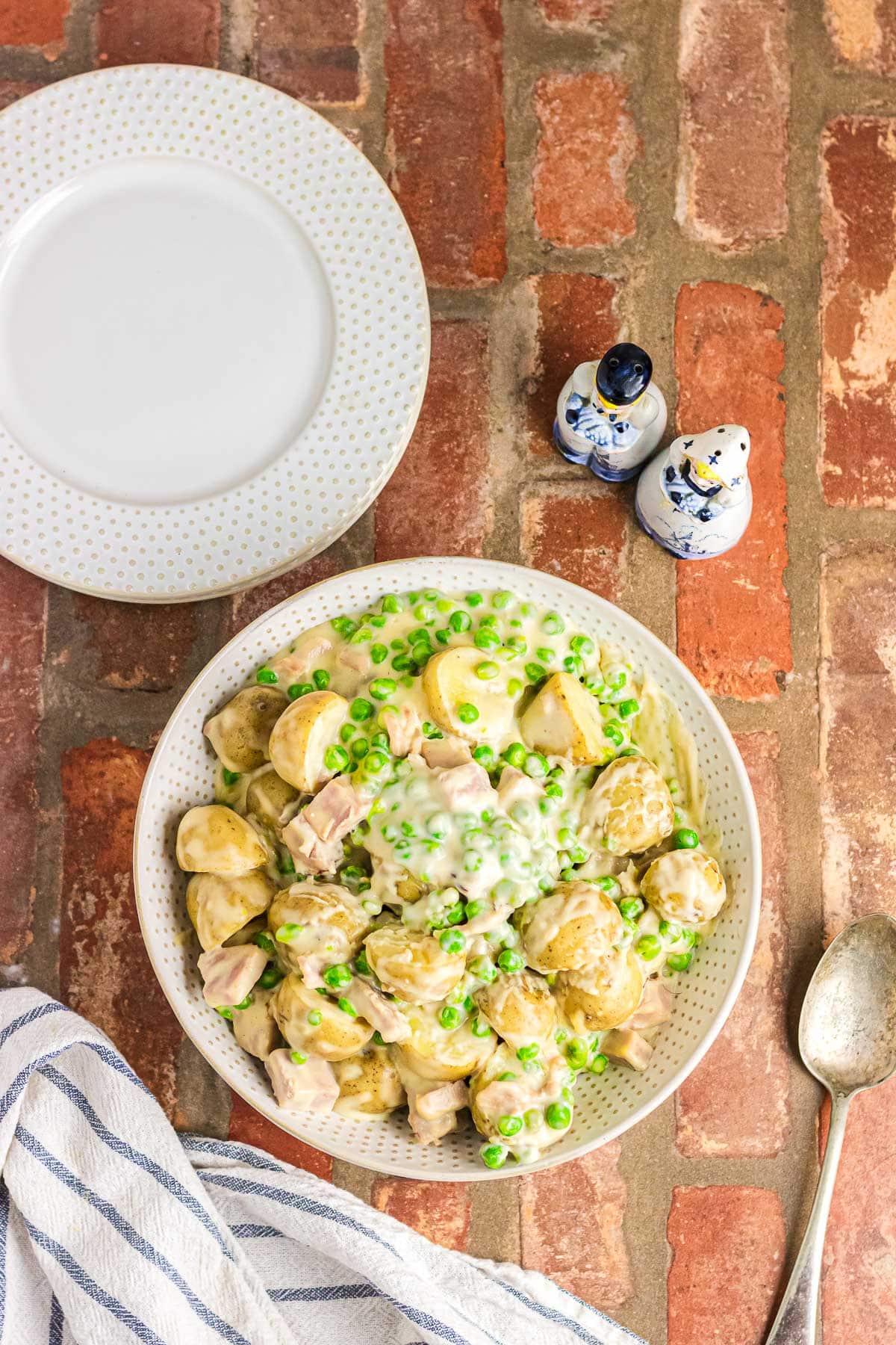 Creamy peas and potatoes in a white serving bowl.