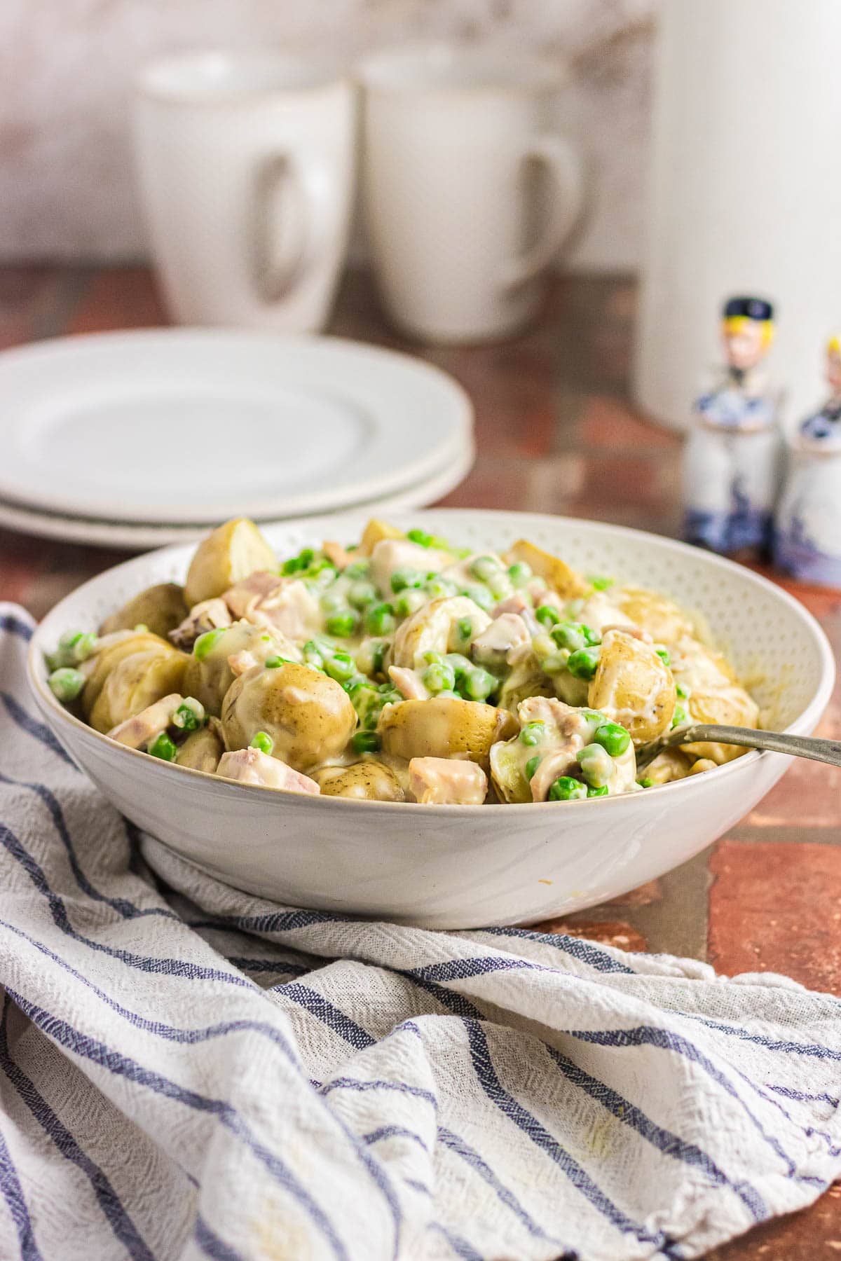 A bowl full of creamed peas and potatoes.