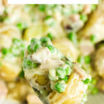A serving spoon filled with creamy peas and potatoes with a text title overlay for Pinterest.
