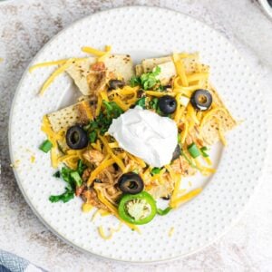 Overhead view of creamy chicken nachos on a plate garnished with sour cream.