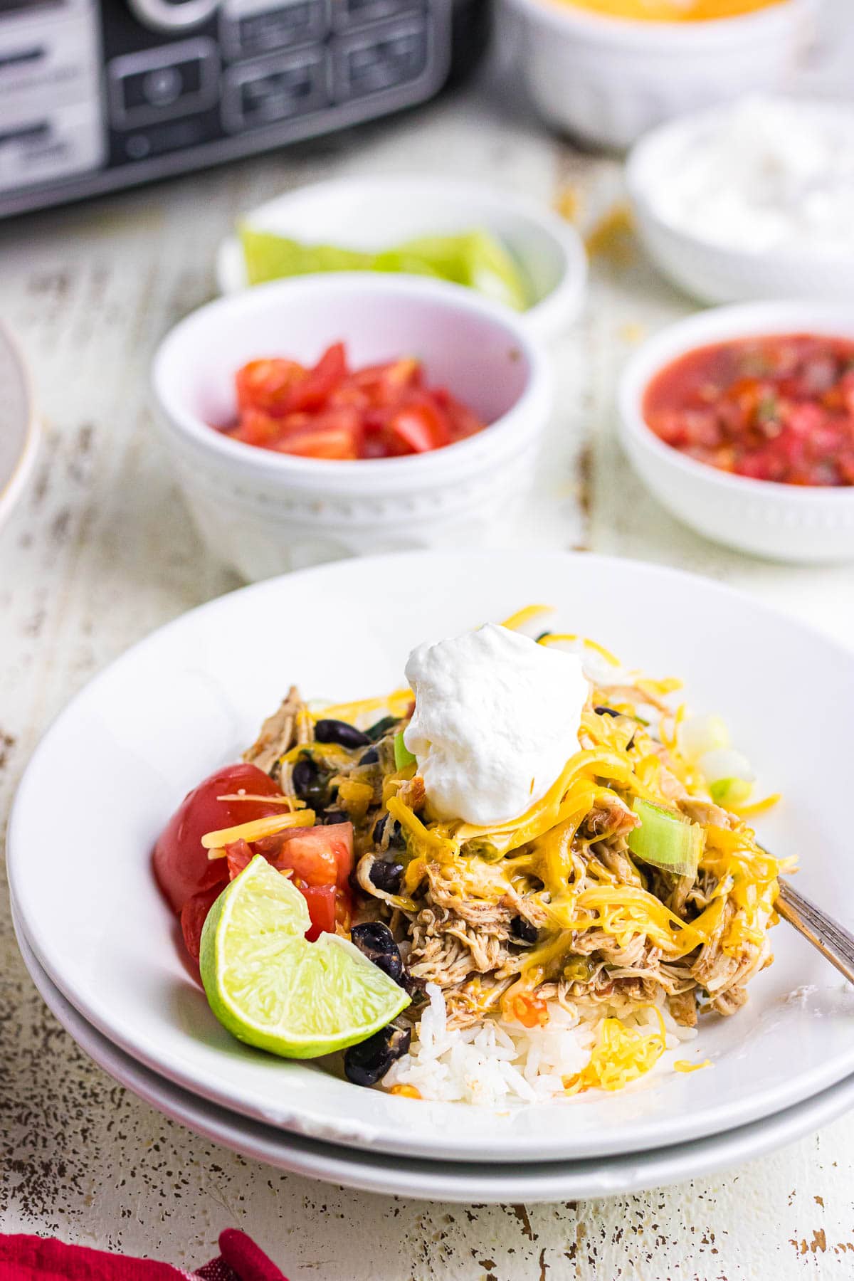 A white plate with rice, chicken, and taco toppings.