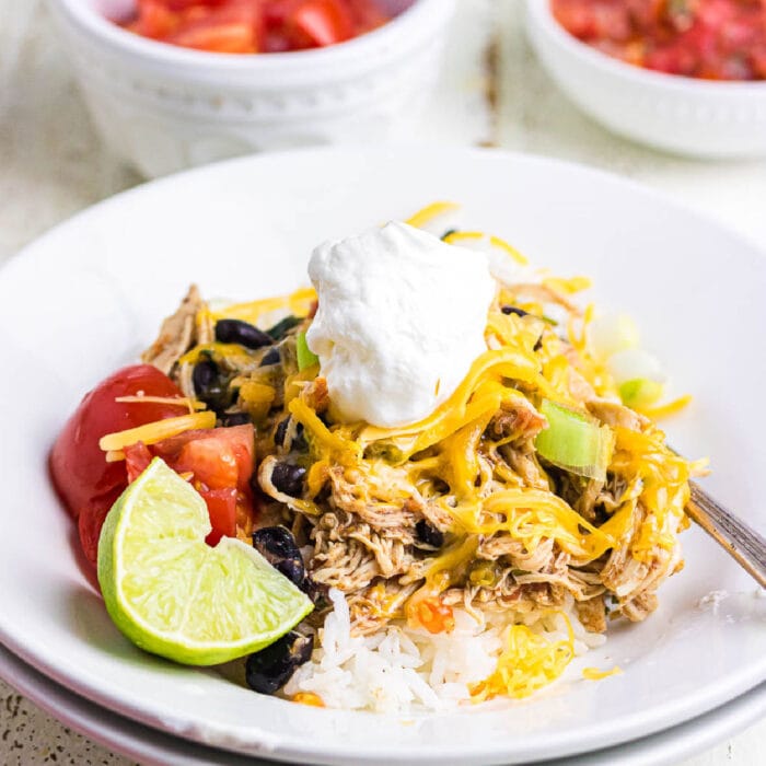 Closeup of the chicken burrito bowl topped with sour cream and garnished with lime.