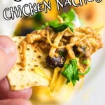 A closeup of a chicken nacho being removed from the plate with a title text overlay for Pinterest.