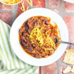 Overhead view of a bowl of chili with grated cheese on top.