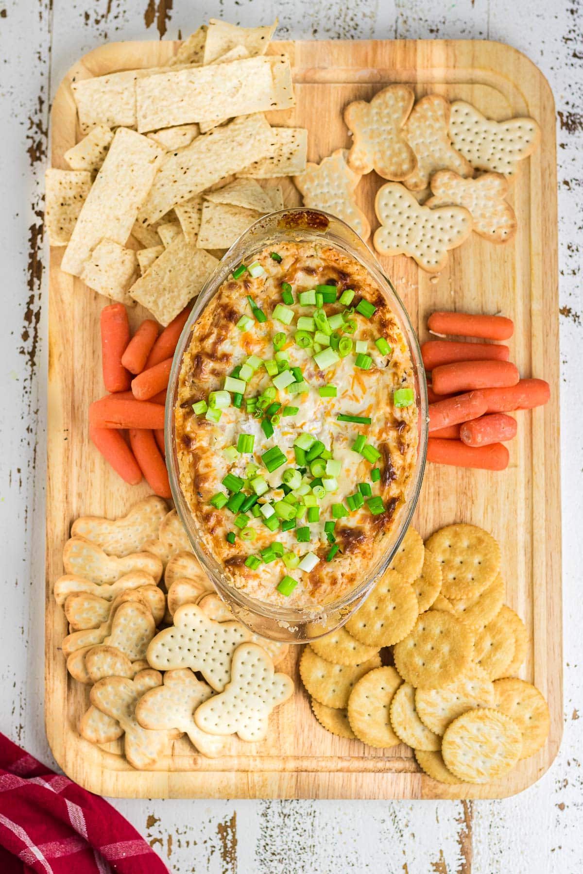 Mississippi Sin Dip on a charcuterie board surrounded by crackers and carrots.