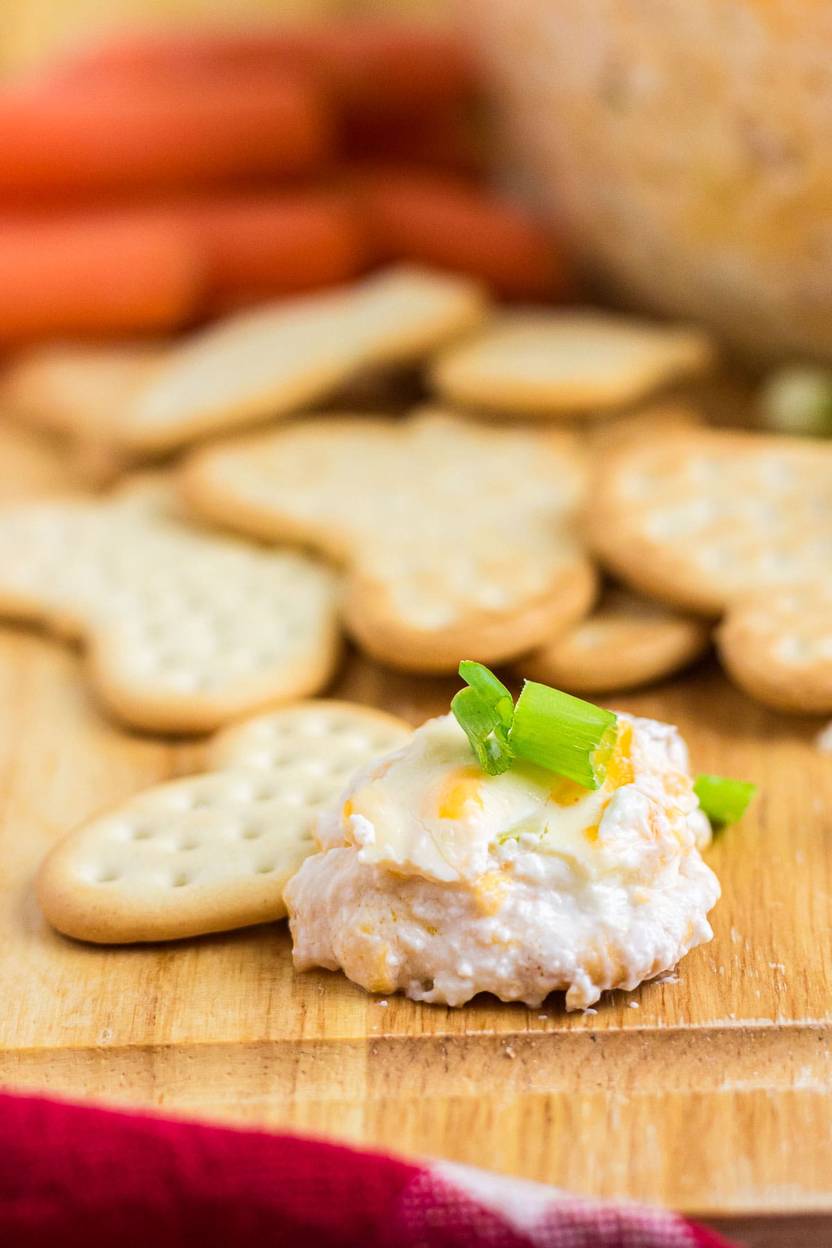 A close-up photo of a dollop of Mississippi sin dip on a cracker, topped with green onion.