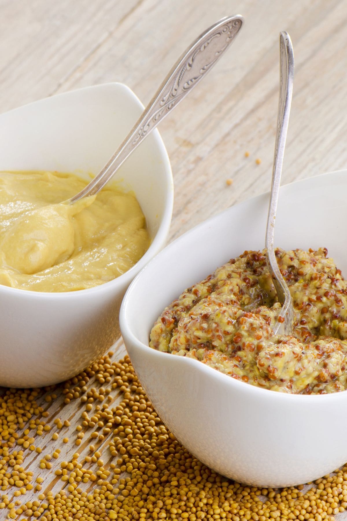 Two bowls of mustard on a white table.