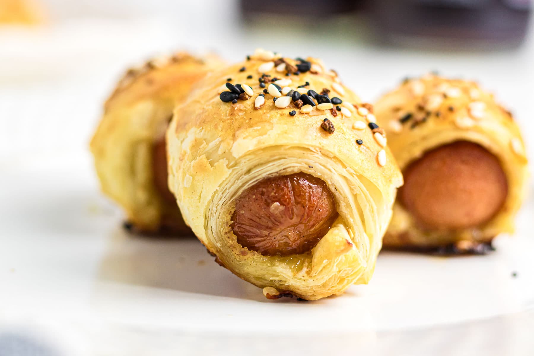 Close-up photo of pigs in a blanket on a white plate.