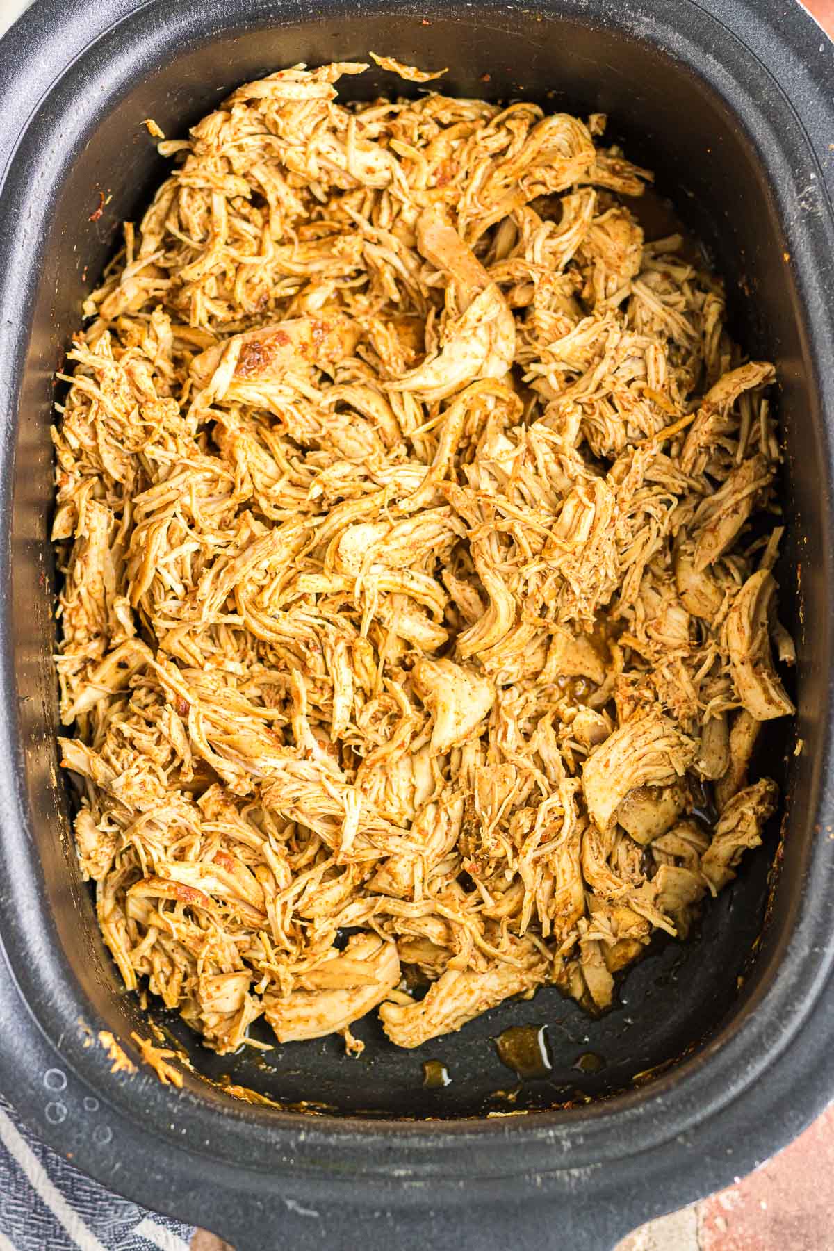 Cooked and shredded chicken in crockpot.
