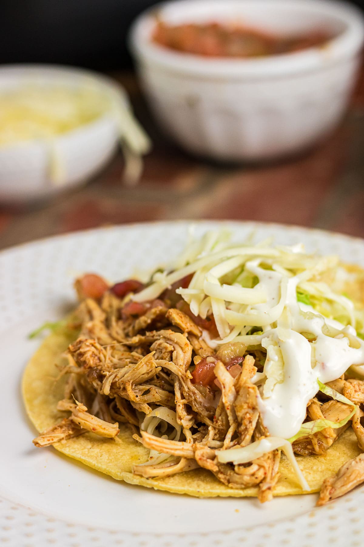 A close-up of a shredded ranch chicken taco with toppings.