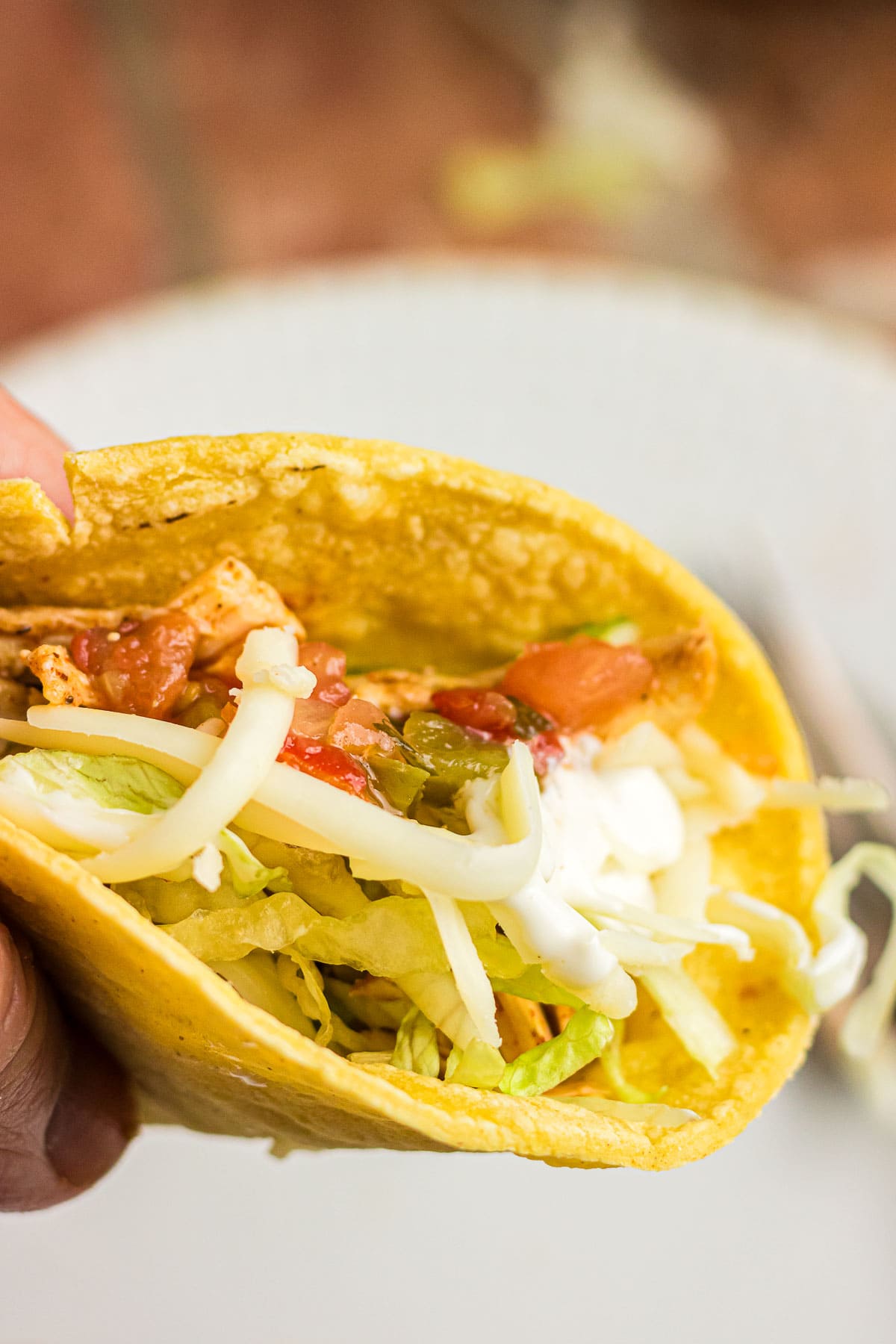 An up-close photo of a chicken ranch taco with cheese and lettuce.