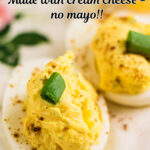 Closeup of a deviled egg on a white egg plate with text overlay for Pinterest.