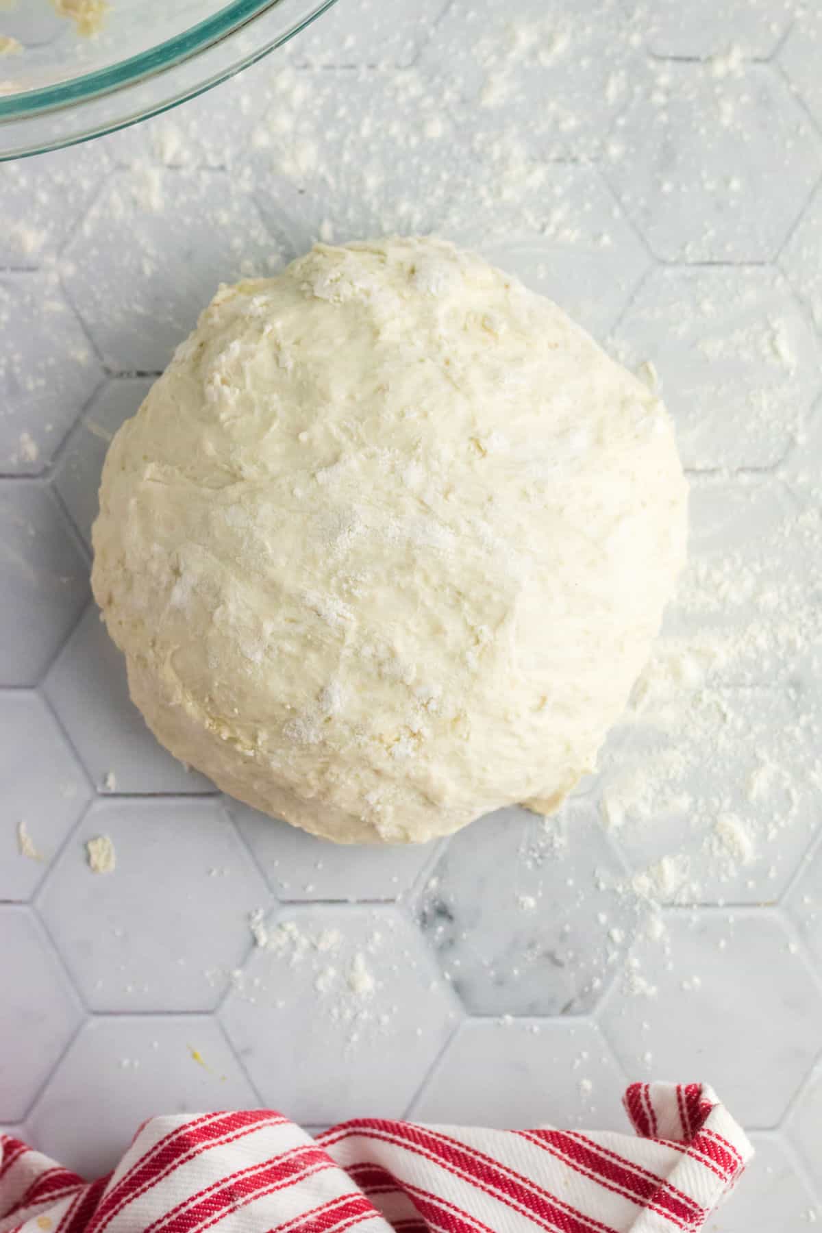 Overhead view of a ball of yeast dough on a countertop.