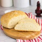 A finished loaf of bread sliced on a bread board.