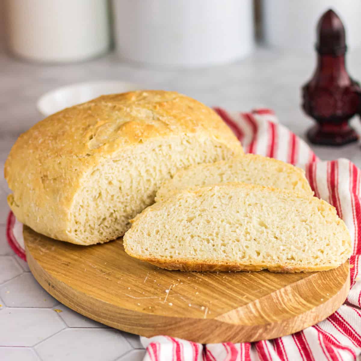 A finished loaf of bread sliced on a bread board.