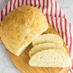 Overhead view of a loaf of bread sliced on a breadboard. Text overlay for Pinterest.